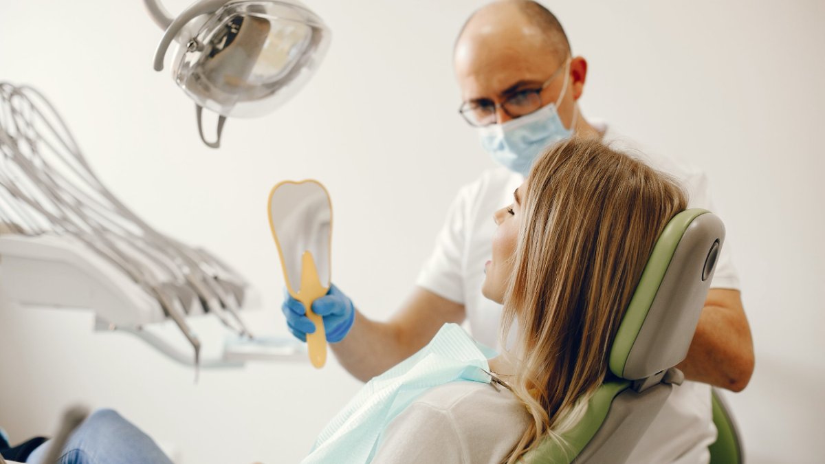 Patient reviewing her teeth with a hand mirror after a dental cleaning at Occlura Dental in Woodbridge